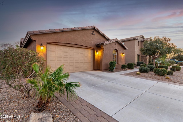 mediterranean / spanish house featuring a garage, concrete driveway, a tile roof, and stucco siding