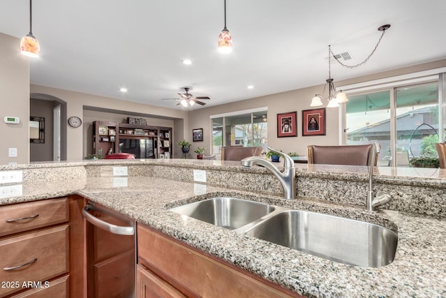 kitchen featuring light stone countertops, pendant lighting, a sink, and recessed lighting