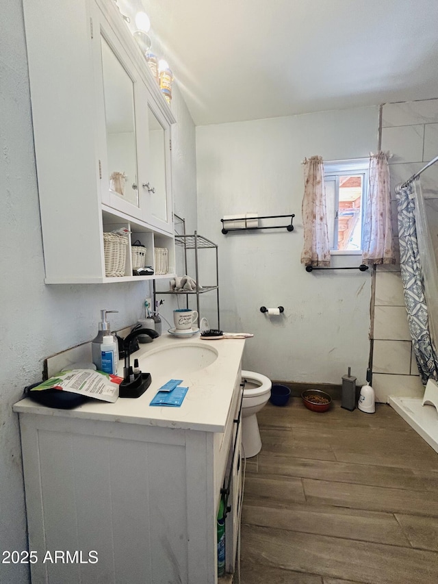 bathroom featuring vanity, hardwood / wood-style floors, walk in shower, and toilet