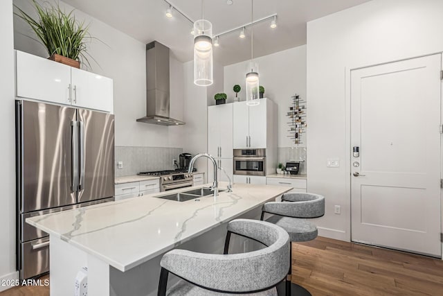 3131 N Central Ave Unit 7004, Phoenix, AZ 85012 - kitchen featuring stainless steel appliances, wall chimney exhaust hood, dark wood-style flooring, a kitchen bar, and decorative light fixtures