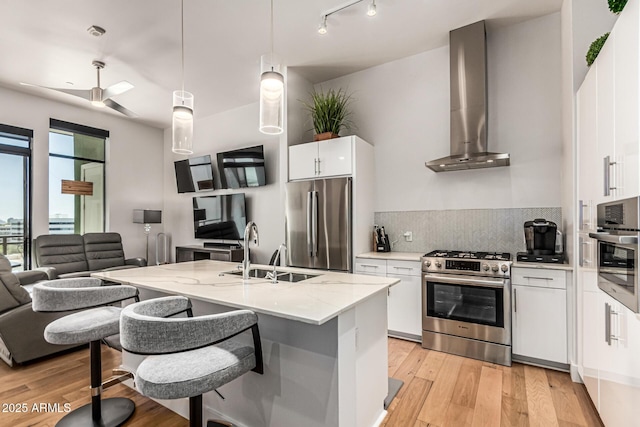 3131 N Central Ave Unit 7004, Phoenix, AZ 85012 - kitchen with appliances with stainless steel finishes, wall chimney exhaust hood, light wood-style flooring, backsplash, and white cabinets
