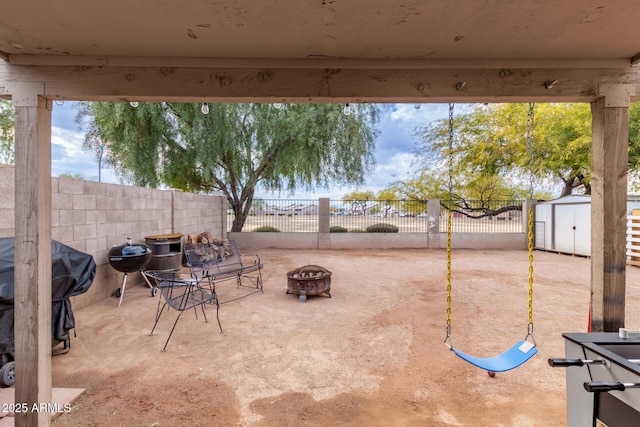 view of patio / terrace featuring a storage shed and an outdoor fire pit