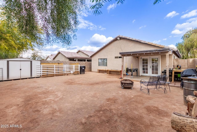 rear view of house featuring french doors, a patio area, a shed, and an outdoor fire pit