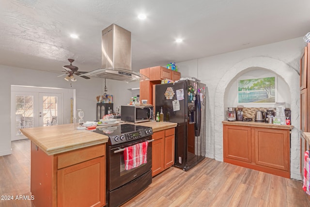 kitchen with black appliances, french doors, island exhaust hood, light hardwood / wood-style floors, and ceiling fan