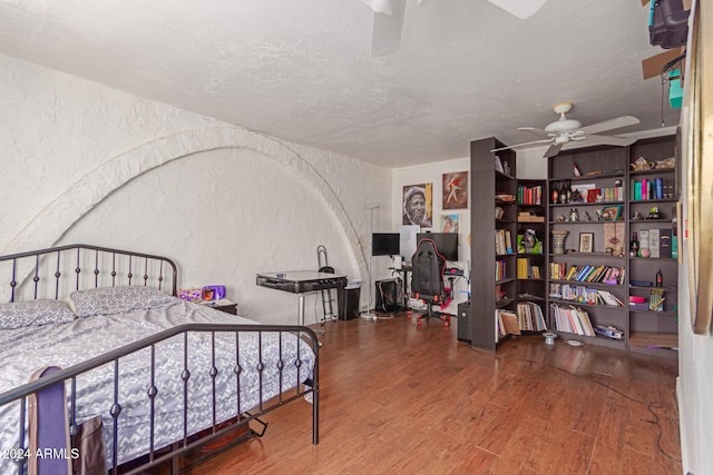 bedroom featuring ceiling fan, wood-type flooring, and a textured ceiling