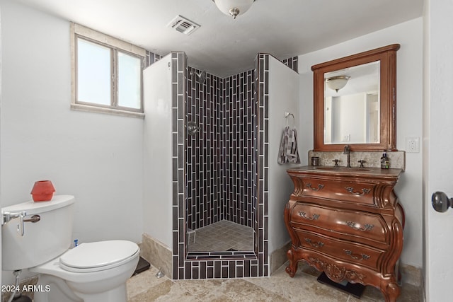 bathroom featuring vanity, a tile shower, and toilet