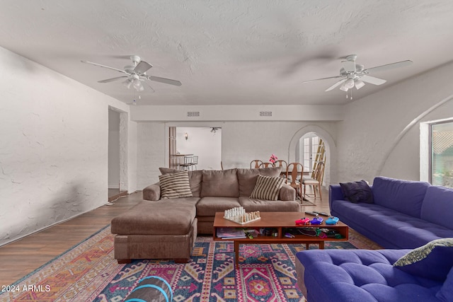 living room with ceiling fan, wood-type flooring, and a textured ceiling