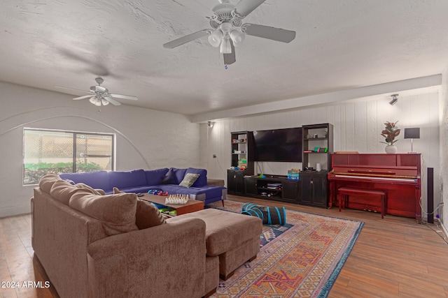 living room with ceiling fan, a textured ceiling, and hardwood / wood-style floors