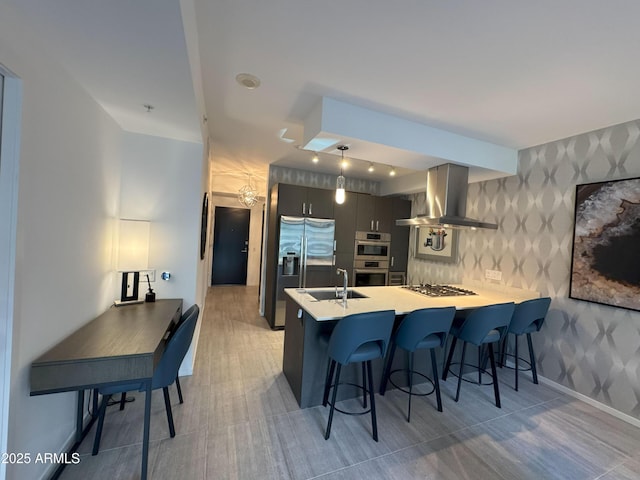 7120 E Kierland Blvd Unit 404, Scottsdale, AZ 85254 - kitchen with wall chimney exhaust hood, wallpapered walls, a peninsula, appliances with stainless steel finishes, and a kitchen bar