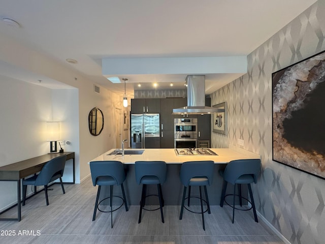 7120 E Kierland Blvd Unit 404, Scottsdale, AZ 85254 - kitchen with island exhaust hood, stainless steel appliances, wallpapered walls, light countertops, and a breakfast bar area