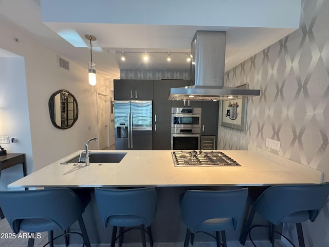 7120 E Kierland Blvd Unit 404, Scottsdale, AZ 85254 - kitchen featuring appliances with stainless steel finishes, island exhaust hood, wallpapered walls, a peninsula, and a breakfast bar area
