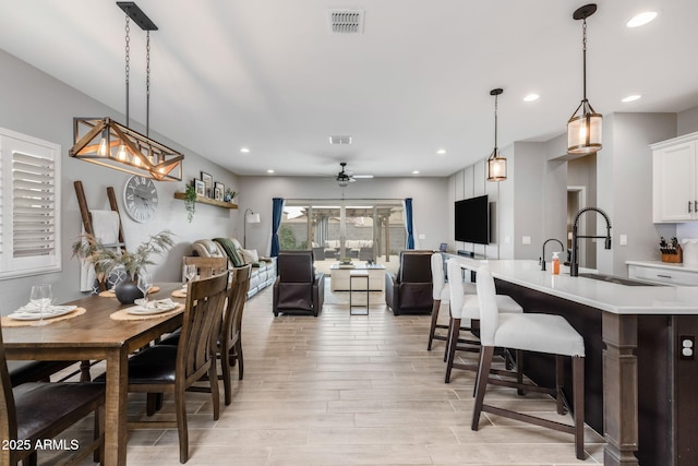 dining space with ceiling fan, sink, and light wood-type flooring