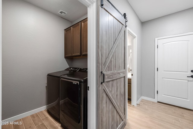 washroom with cabinets, a barn door, and independent washer and dryer