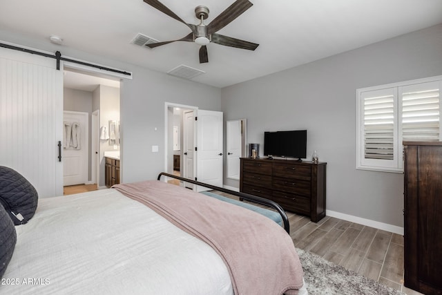 bedroom with ceiling fan, connected bathroom, and a barn door