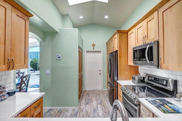15558 N Ulrich Way, Surprise, AZ 85374 - kitchen featuring appliances with stainless steel finishes, decorative backsplash, light wood finished floors, light countertops, and arched walkways