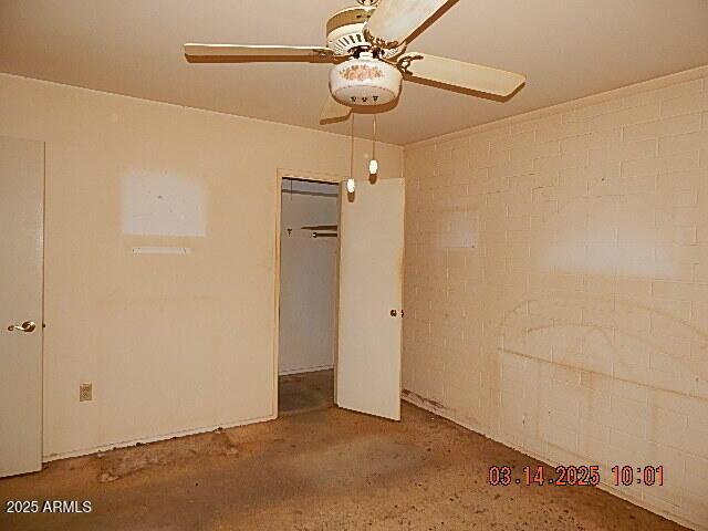 unfurnished bedroom with ceiling fan, a closet, and brick wall