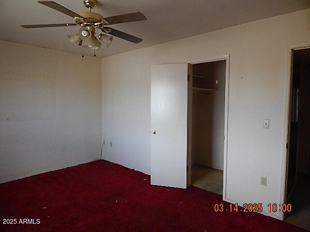 unfurnished bedroom with a closet, carpet flooring, and a ceiling fan