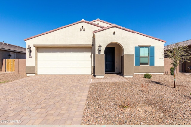 mediterranean / spanish home featuring a garage, decorative driveway, a tiled roof, and stucco siding