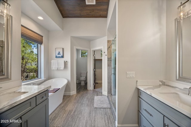full bathroom featuring a stall shower, a sink, a freestanding bath, and baseboards