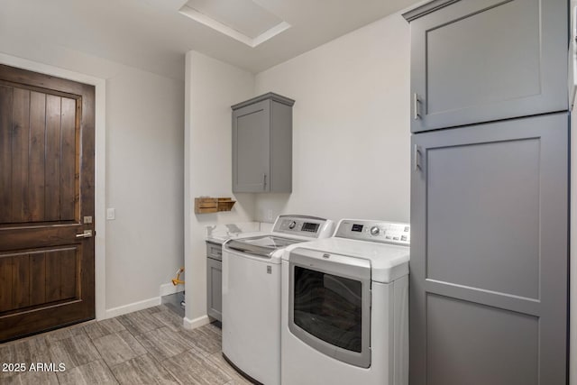 laundry area featuring cabinet space, light wood-style floors, attic access, baseboards, and washer and clothes dryer
