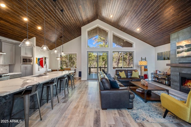living room with recessed lighting, a fireplace, high vaulted ceiling, light wood-style flooring, and wood ceiling