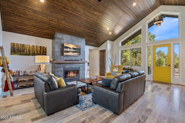 living room featuring a tile fireplace, wooden ceiling, light wood-style flooring, and high vaulted ceiling