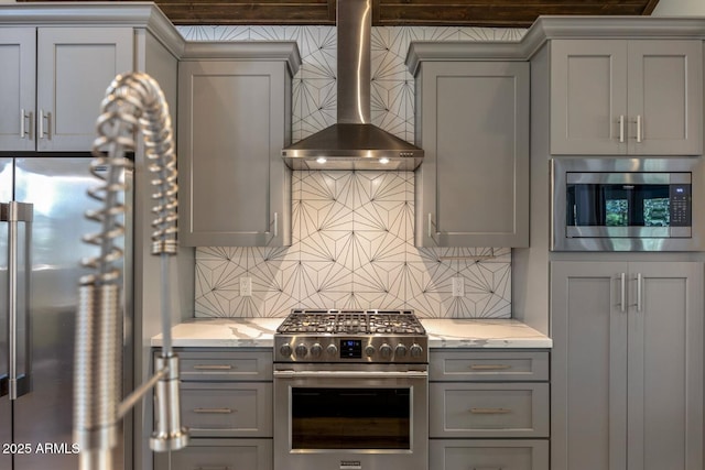 kitchen with gray cabinets, high quality appliances, and wall chimney range hood