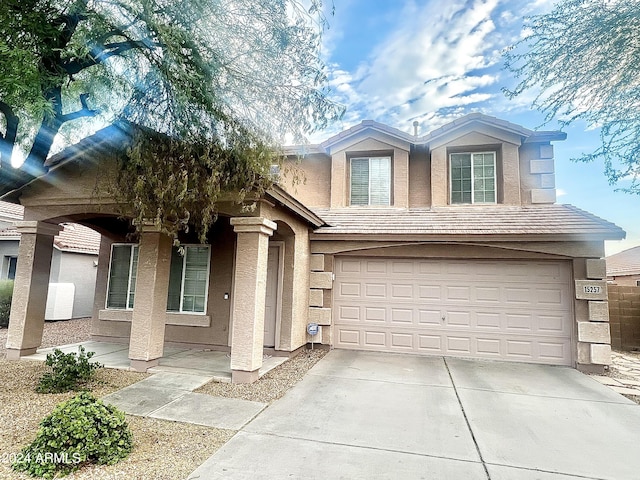 view of front of home with a porch, an attached garage, concrete driveway, a tiled roof, and stucco siding