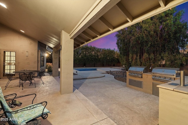 patio terrace at dusk with a grill and exterior kitchen