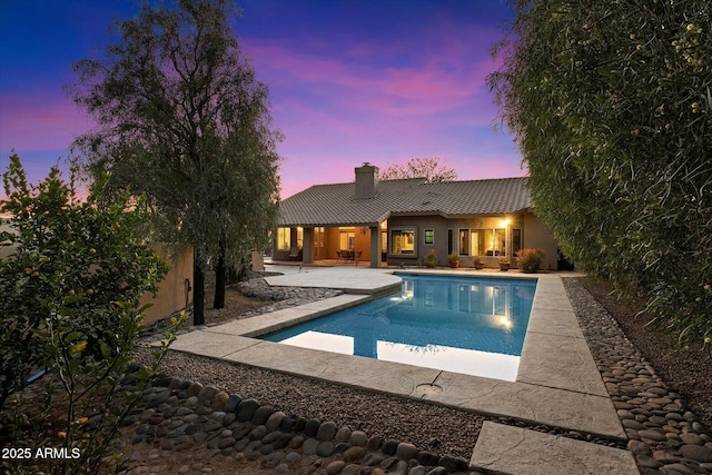 pool at dusk featuring a patio area