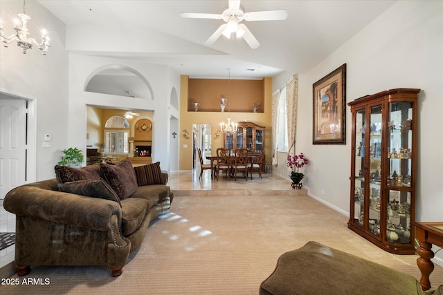 living room featuring light carpet, ceiling fan with notable chandelier, and a high ceiling