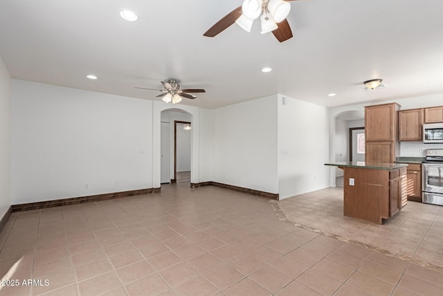 kitchen with ceiling fan, stainless steel appliances, a center island, and light tile patterned floors