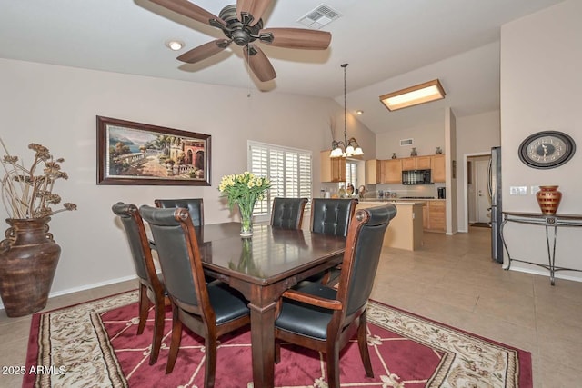 tiled dining room with lofted ceiling and ceiling fan with notable chandelier