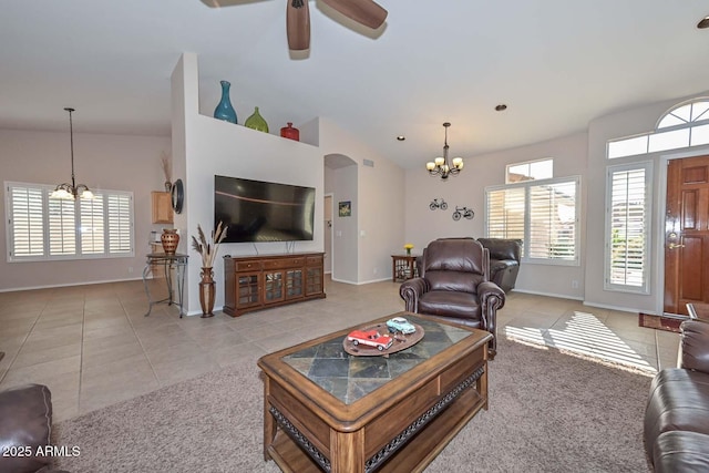 living room with vaulted ceiling, ceiling fan with notable chandelier, and light tile patterned floors