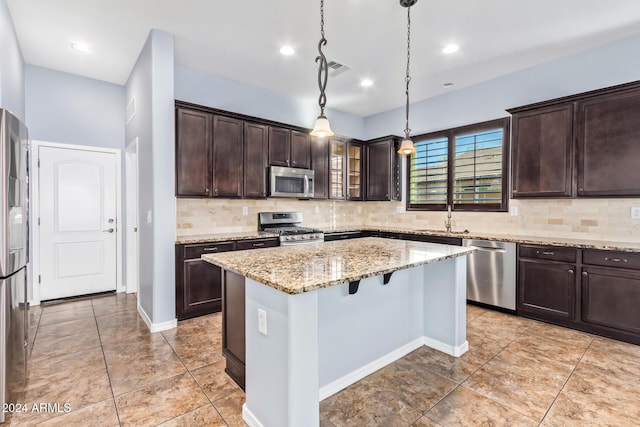 kitchen featuring tasteful backsplash, dark brown cabinets, stainless steel appliances, a kitchen island, and hanging light fixtures