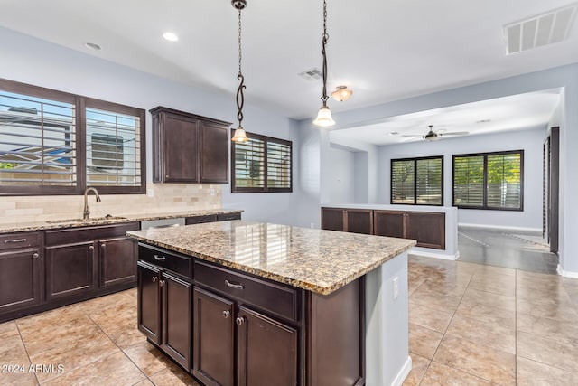 kitchen with decorative backsplash, ceiling fan, sink, a center island, and hanging light fixtures