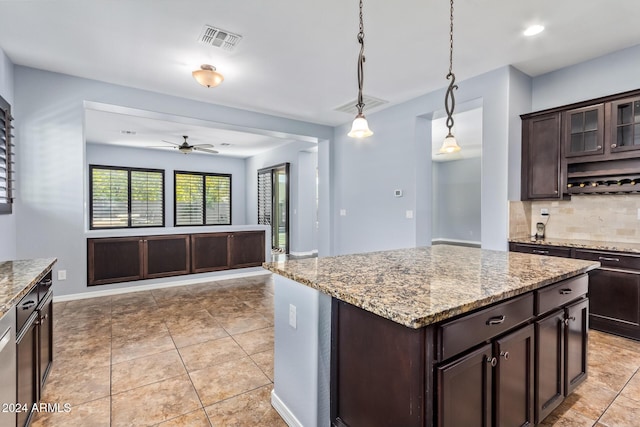 kitchen with dark brown cabinetry, ceiling fan, tasteful backsplash, pendant lighting, and a kitchen island