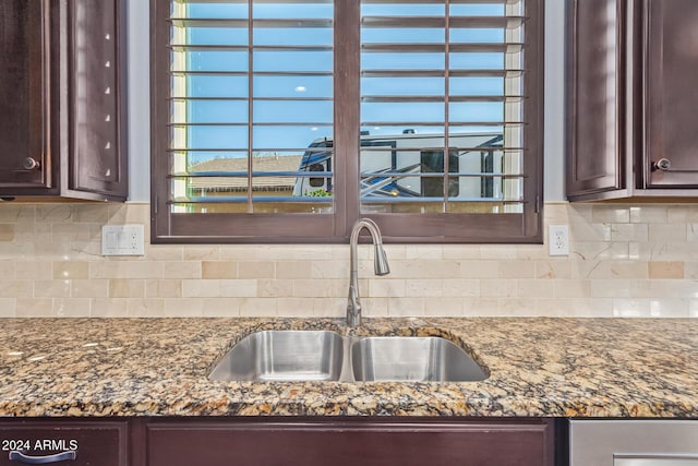 kitchen featuring tasteful backsplash, dark stone countertops, and sink