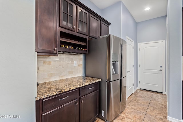 kitchen featuring decorative backsplash, stainless steel refrigerator with ice dispenser, dark stone counters, dark brown cabinetry, and light tile patterned floors