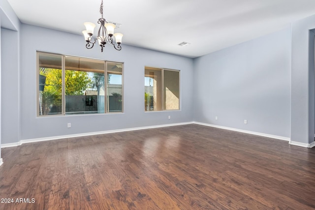 empty room featuring dark hardwood / wood-style flooring and a chandelier