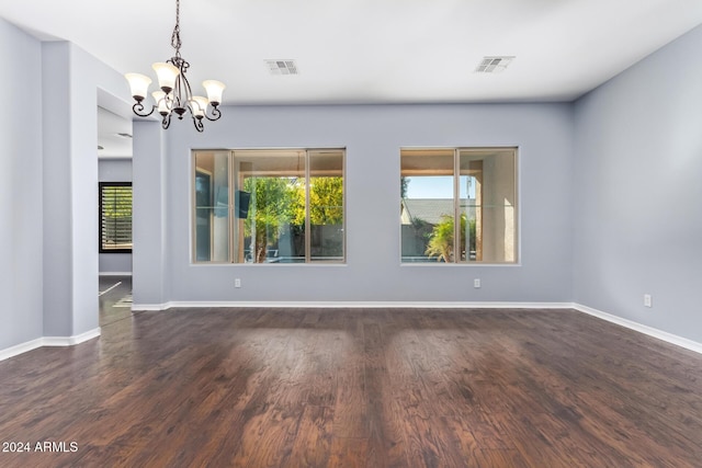 unfurnished room featuring dark wood-type flooring and an inviting chandelier