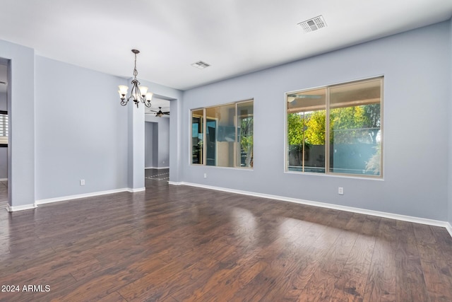 empty room with ceiling fan with notable chandelier and dark hardwood / wood-style floors