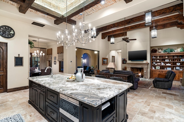 kitchen featuring pendant lighting, sink, a kitchen island with sink, and beamed ceiling