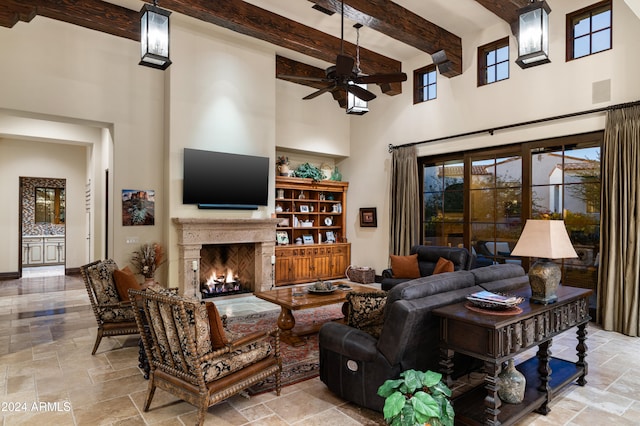 living room featuring beamed ceiling, a high ceiling, and ceiling fan