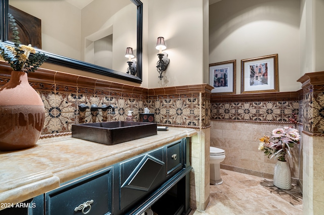 bathroom with vanity, toilet, and tile walls