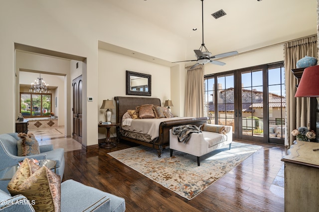 bedroom with french doors, dark hardwood / wood-style floors, a towering ceiling, access to outside, and ceiling fan with notable chandelier