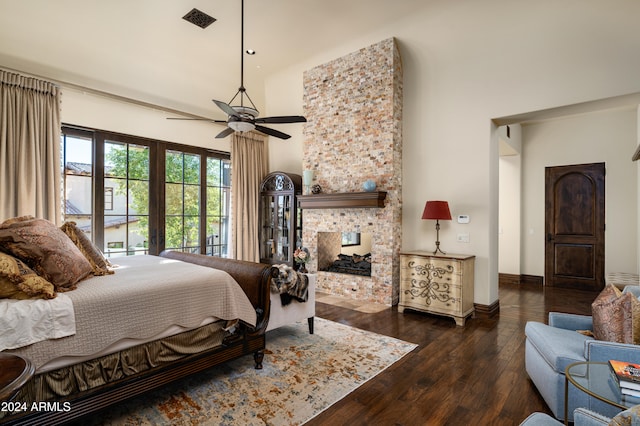 bedroom with a multi sided fireplace, a high ceiling, dark hardwood / wood-style flooring, and ceiling fan