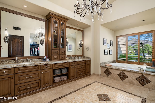 bathroom with a chandelier, vanity, and tiled tub