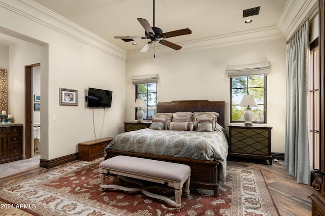 bedroom featuring hardwood / wood-style floors, multiple windows, crown molding, and ceiling fan