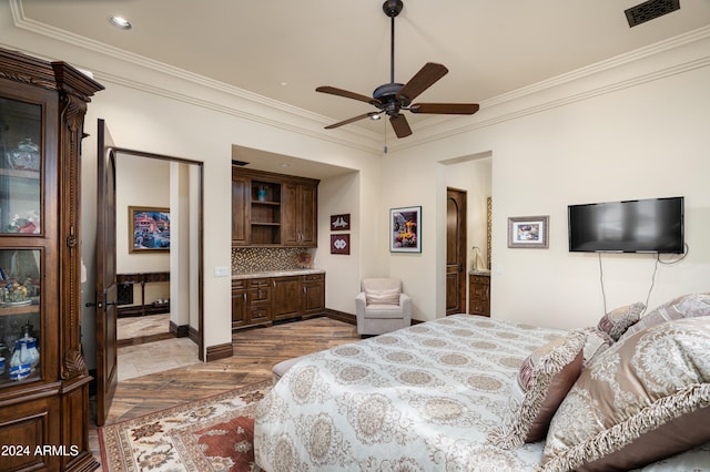 bedroom featuring connected bathroom, light hardwood / wood-style flooring, ceiling fan, and crown molding